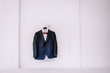 Valmiera, Latvia - August 19, 2023 - A navy blue suit with a white shirt and red bow tie, hanging...