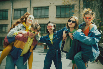 Joyful urban fashion vibe. Lively group of five friends enjoy sunny day on rooftop, wearing stylish denim clothes. Carefree, youthful spirit. Concept of 90s, fashion, youth culture, old-style trends