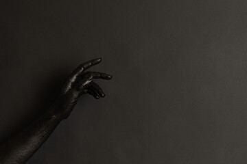 Woman's hands with black paint on her skin on dark background. High Fashion art concept