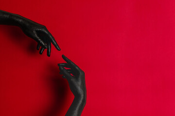 Black color painted woman's hands on her skin with red background. High Fashion art concept