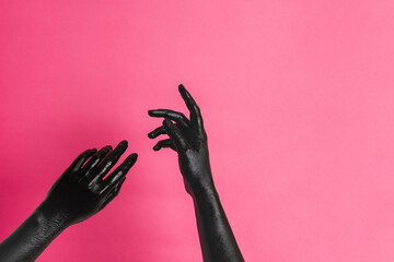 Elegant woman's hands with black paint on her skin on pink background. High Fashion art concept