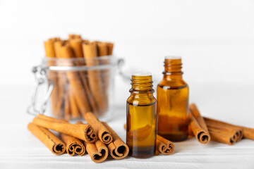 Cinnamon aromatic essential oil and cinnamon sticks on a wooden background. Aromatherapy. Organic...