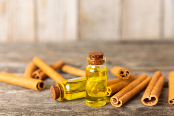 Cinnamon aromatic essential oil and cinnamon sticks on a wooden background. Aromatherapy. Organic cosmetic oil. Spa concept. Place for text. Copy space.