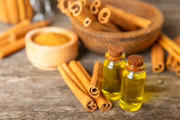 Cinnamon aromatic essential oil and cinnamon sticks on a wooden background. Aromatherapy. Organic cosmetic oil. Spa concept. Place for text. Copy space.