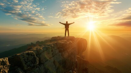 A human silhouette stands at a canyon's edge, arms outstretched basking in brilliant sunrays piercing the sky by majestic mountains. Hope, inspiration, elation upon achieving a goal or dream
