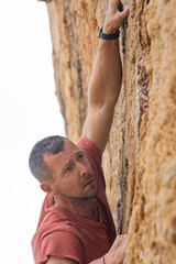 A man in a red shirt is climbing a rock wall