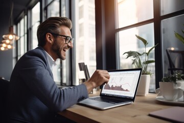 Joyful man in smart casual outfit using laptop, displaying graphs, laughing in modern office with daylight and plants. Ideal for themes of success, business analytics, and workplace enthusiasm
