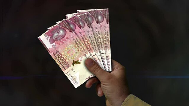 Guinea Franc money holding. Fan of banknotes in hand. Guinean GNF paper cash. Concept of income, success, business, tax, economy and finance.