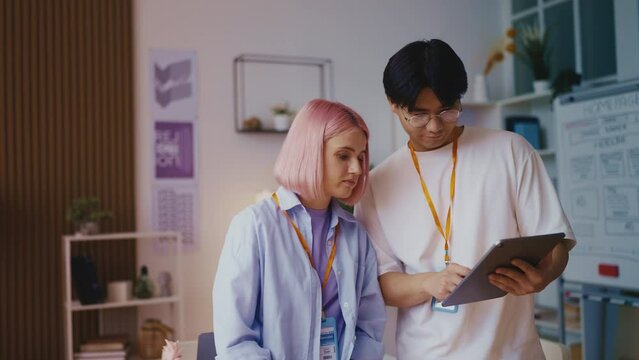 Asian man web designer discussing project with his female colleague, teamwork