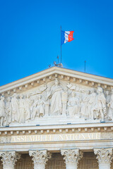French flag and facade of the Assemblee Nationale building in Paris, France