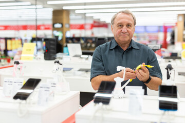 Elderly male customer looking for a deal on smart watches in big electronics store
