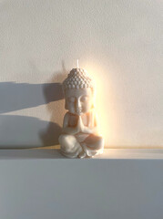 white candle made of soy wax with the image of the god Buddha