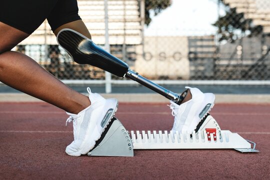 Paralympic athlete with prosthetic leg waiting to take off on sprint starting blocks