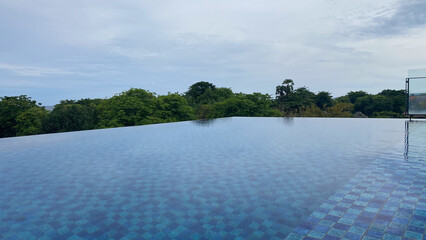 infinite swimming pool with a blue water and trees in the background in bali