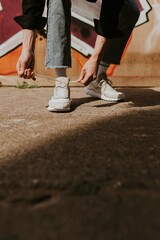 Man tying shoelaces, closeup shot, graffiti wall