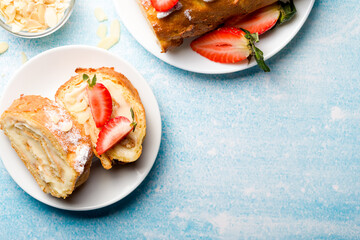 Sliced rolls with custard. The dessert is decorated with fresh strawberries.
