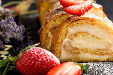 Sliced rolls with custard. The dessert is decorated with fresh strawberries.