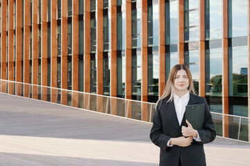 Businesswoman in a black suit with a folder in her hands in front of office building