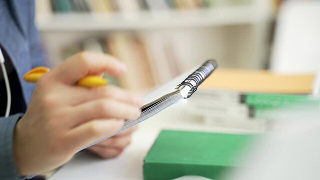 Close up. A female hand writes with a pen in a notebook at the university library. Student taking notes, reading textbook, learning on the examination period. Applicant prepares for the entrance exams