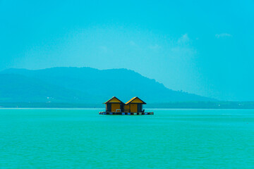 Small floating houses between the horizon line that separates the sea from the sky and set against...