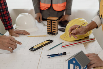 A diverse team of experts works on a real estate construction project with civil engineers, architects, business investors and general workers discussing detailed plans.
building a house