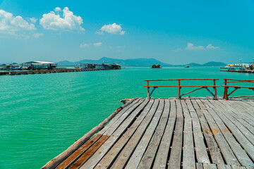 Obraz premium Small floating houses between the horizon line that separates the sea from the sky and set against a backdrop of plains and mountains. Floating houses used by fishermen as a place to cultivate fish