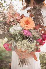 A beautiful woman holds a bouquet of flowers and herbs in her hands. Romantic mood