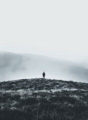 Man standing alone on a hilltop overlooking a foggy landscape