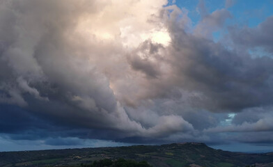 Enorme nuvola bianca sopra il paese in cima alla collina porta la pioggia in una giornata di sole...