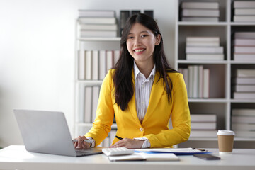Portrait of attractive Asian businesswoman at desk in office.