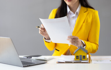Real estate agent presenting residential building and house sale contract to sign. Businesswoman in office working with house and land sales contract documents.