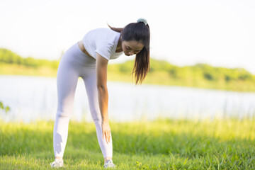 Beautiful Asian woman warms up and stretches before jogging in the park.