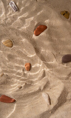 Beach sand with marine stones under the water texture shadows close up