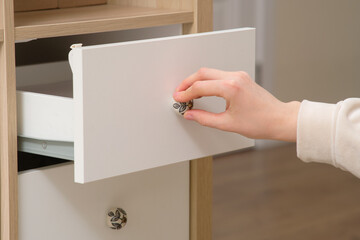 A woman's hand opens a drawer, close-up. Cabinet drawer