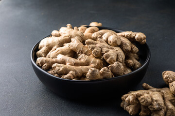 Ginger roots from the garden in plate on black surface