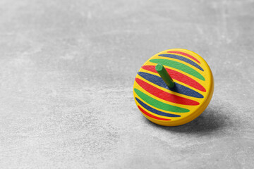 Bright spinning top on grey textured background, closeup. Space for text