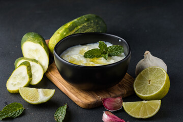 A bowl of tzatziki dip and fresh cut vegetable sticks next to it