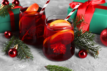 Delicious Sangria drink in glasses and Christmas decorations on grey textured table, closeup