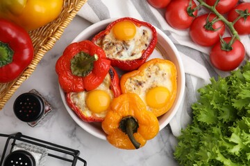 Delicious stuffed peppers with eggs in bowl and ingredients on white marble table, flat lay