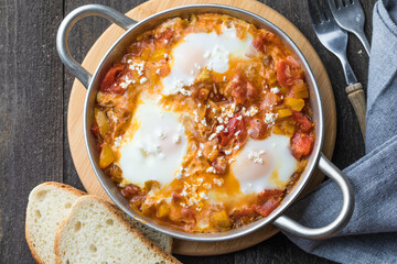 Shakshuka with eggs tomato and parsley in a cast iron pan.