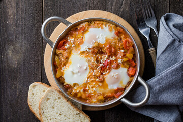 Shakshuka with eggs tomato and parsley in a cast iron pan.