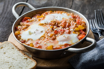 Shakshuka with eggs tomato and parsley in a cast iron pan.