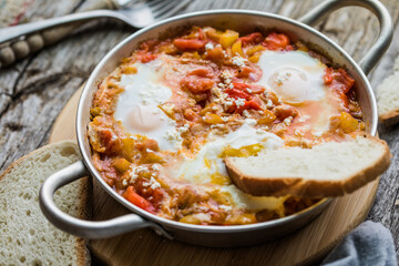 Shakshuka with eggs tomato and parsley in a cast iron pan.