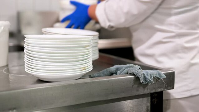 Cleaner staff collecting dirty dishes and put them onto sink in restaurant Kitchen. High quality 4k footage