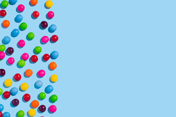 Multicolored candies on a bright pink background. Colorful summer idea with copy space.