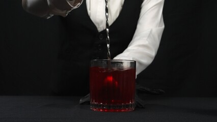 Macrography, observe the expertise of a bartender as stir a Rosemary Cranberry Martini against a...