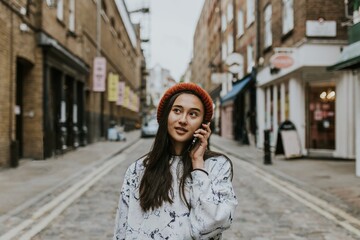 Obraz premium Young woman talking on a phone while in a city