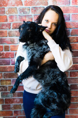 Happy brunette lady in casual wear hugging mudi pet dog, studio background.
