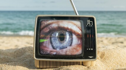 televisions with beautiful female eye on the screen next to the sea - 801284221