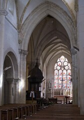 Fototapeta premium Sainte-Marie-du-Mont, France - Apr 20, 2024: Sainte-Marie-du-Mont church. People walking in Sainte-Marie-du-Mont. Streets and buildings. Lifestyle in the urban area. Sunny spring day. Selective focus.